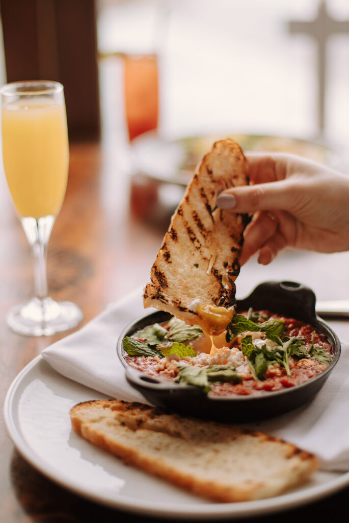 Undistinguishable person dipping bread into a cast iron skillet food dish